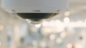 Close-up view of an Axis brand dome camera placed on the ceiling in a store.