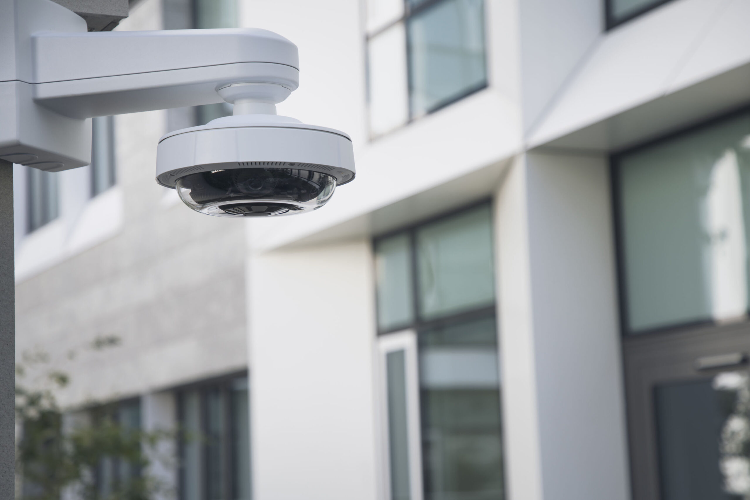 A panoramic dome video security camera placed on a pole to monitor the outside of a building.